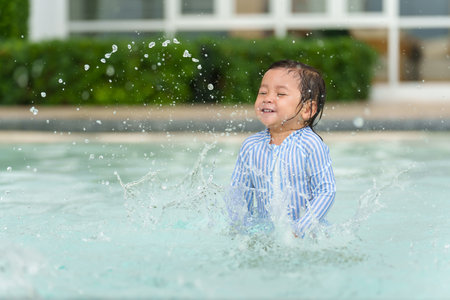happy toddler baby playing water splashing in the swimming poolの写真素材