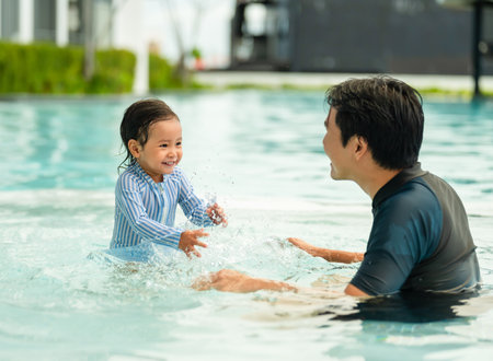 happy father with todler baby playing water splashing in a swimming poolの写真素材