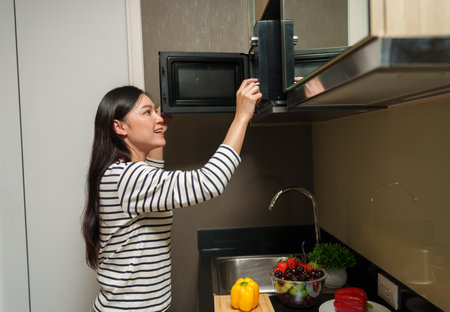 woman cooking with a microwave in the kitchen roomの写真素材