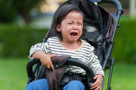 toddler baby crying while sitting in stroller in the park