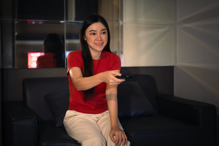 happy woman watching TV on a sofa at nightの写真素材