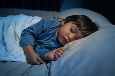 toddler baby sleeping on a bed at nightの写真素材