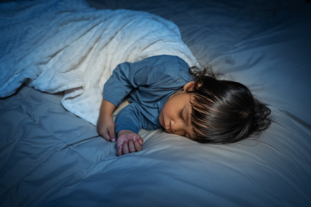 toddler baby sleeping on a bed at nightの写真素材