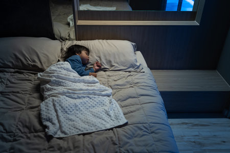 toddler baby sleeping on a bed at nightの写真素材