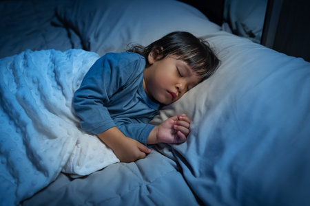 toddler baby sleeping on a bed at nightの写真素材