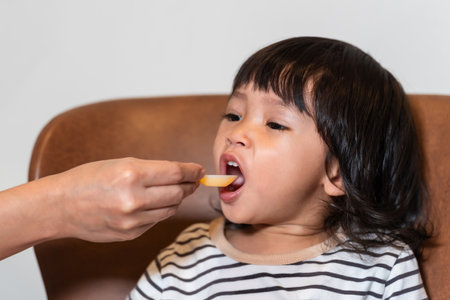 mother feeding liquid medicine to sick toddler baby with a spoonの写真素材