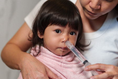 mother making nasal wash for toddler with a syringe and saline. cleaning baby noseの写真素材