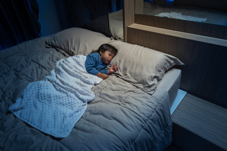 toddler baby sleeping on a bed at nightの写真素材