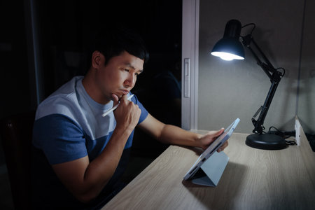 man thinking while using tablet at a nightの写真素材