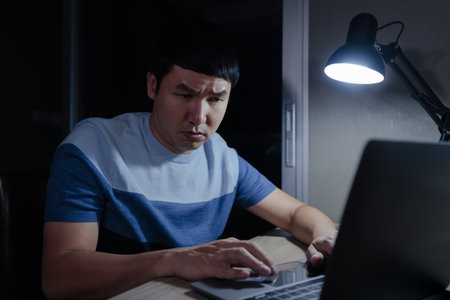 stressed man working with laptop at a nightの写真素材