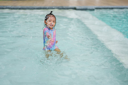 happy toddler baby girl playing water splashing in a swimming poolの写真素材