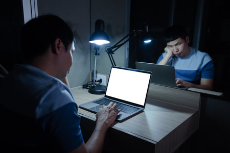 bored man working with laptop at a night (with clipping path)の写真素材