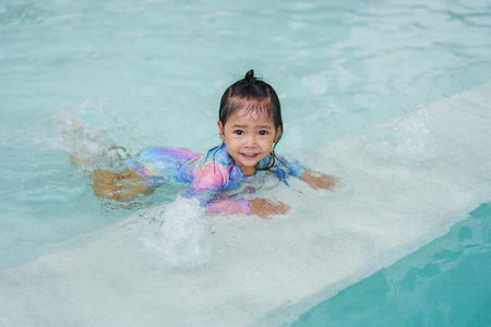 toddler baby girl learning to swim in edge of a poolの写真素材