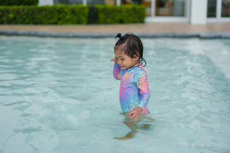 happy toddler baby playing water in a swimming poolの写真素材