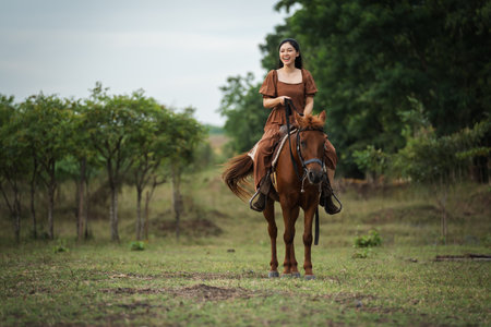 happy woman riding brown horse on meadow fieldの写真素材