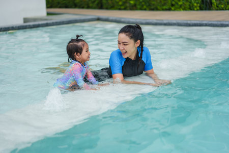 happy mother with toddler baby girl in edge of a swimming poolの写真素材