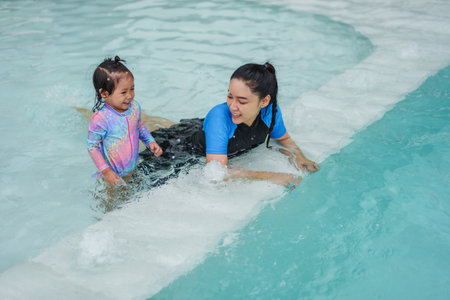 happy mother with toddler baby girl in edge of a swimming poolの写真素材