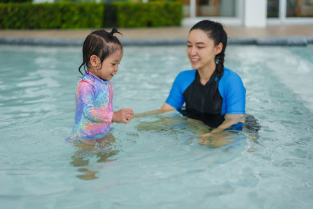happy mother with toddler baby girl in a swimming poolの写真素材