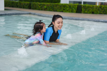 happy mother with toddler baby girl in edge of a swimming poolの写真素材