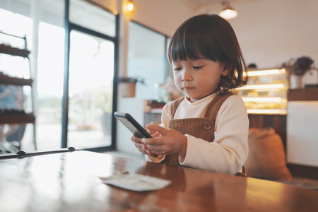 toddler girl using a smartphone at cafeの写真素材