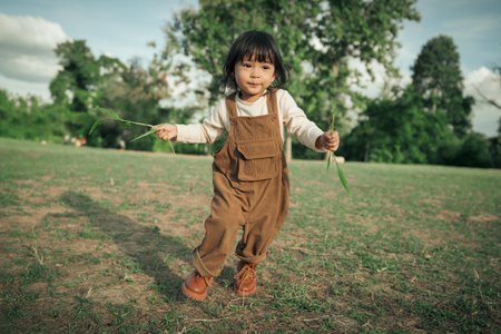 happy toddle baby girl running on a grass fieldの写真素材