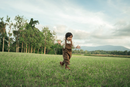 happy toddle baby girl running on a grass fieldの写真素材