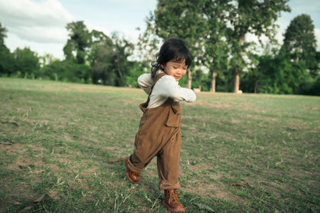 happy toddle baby girl running on a grass fieldの写真素材