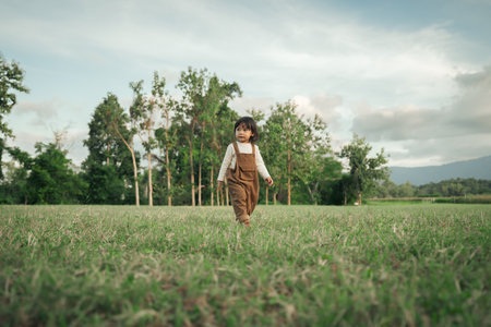 happy toddle baby girl walking on a grass fieldの写真素材