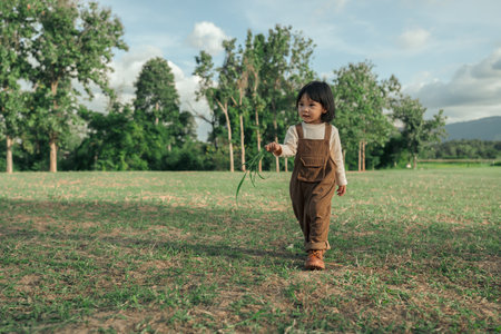 happy toddle baby girl walking on a grass fieldの写真素材