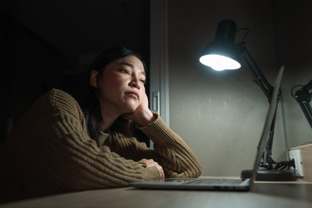 bored woman working with laptop at a nightの写真素材