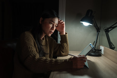 stressed woman using tablet at a nightの写真素材