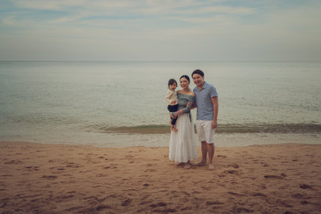 toddler baby girl with her father and mother. happy family on the sea beach  in Pattaya, Thailandの写真素材