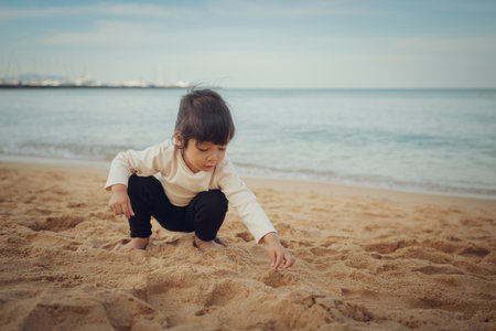toddler baby girl playing sand on the sea beach in Pattaya, Thailandの写真素材