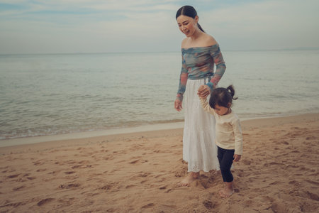 toddler baby girl walking with mother on the sea beach in Pattaya, Thailandの写真素材