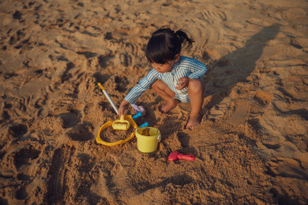 happy toddler baby girl playing sand toy on the sea beach in Pattaya, Thailandの写真素材