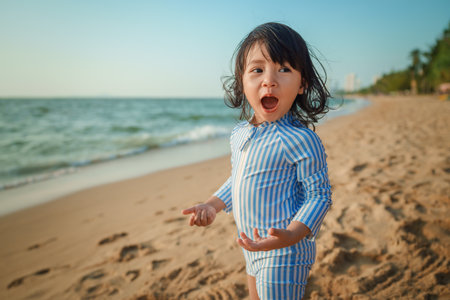 cheerful toddler baby girl standing on the sea beach in Pattaya, Thailandの写真素材