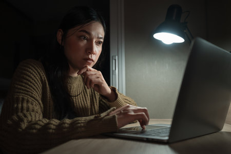 woman thinking and working with laptop at a nightの写真素材