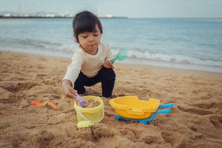 toddler baby girl playing sand toy on the sea beach in Pattaya, Thailandの写真素材