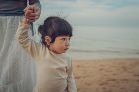 toddler baby girl walking with mother on the sea beach in Pattaya, Thailandの写真素材