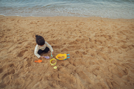 toddler baby girl playing sand toy on the sea beach in Pattaya, Thailandの写真素材