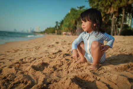toddler baby girl sitting on the sea beach in Pattaya, Thailandの写真素材