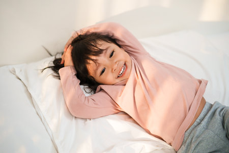 happy toddler girl smilling on a bedの写真素材