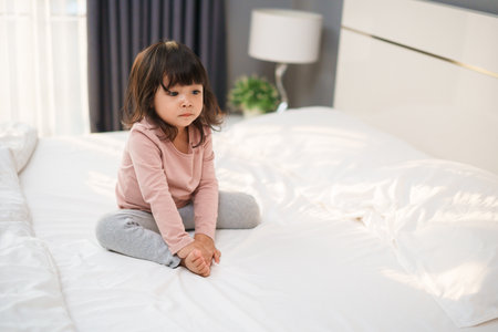 toddler girl sitting on a bedの写真素材