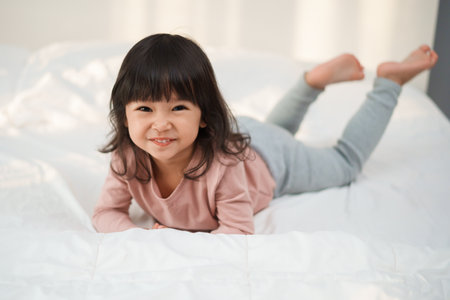 happy toddler girl smilling on a bedの写真素材