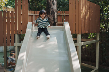 toddler baby girl sliding and playing at outdoor playgroundの写真素材
