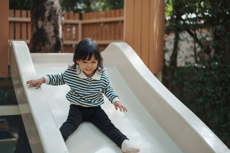 toddler baby girl sliding and playing at outdoor playgroundの写真素材