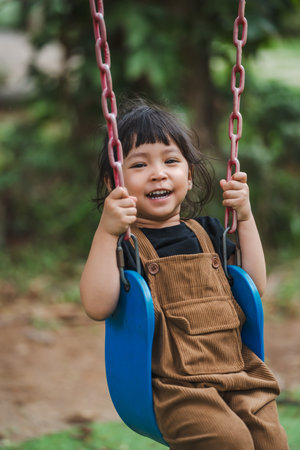 cheerful toddler girl playing on a swingの写真素材