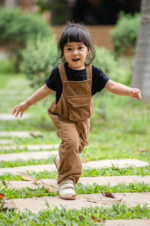 happy toddler girl walking on a stone pathway in gardenの写真素材