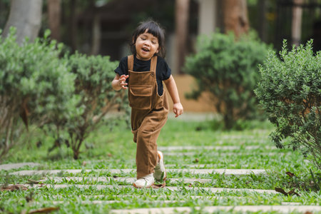 happy toddler girl walking on a stone pathway in gardenの写真素材