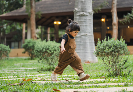 happy toddler girl walking on a stone pathway in gardenの写真素材